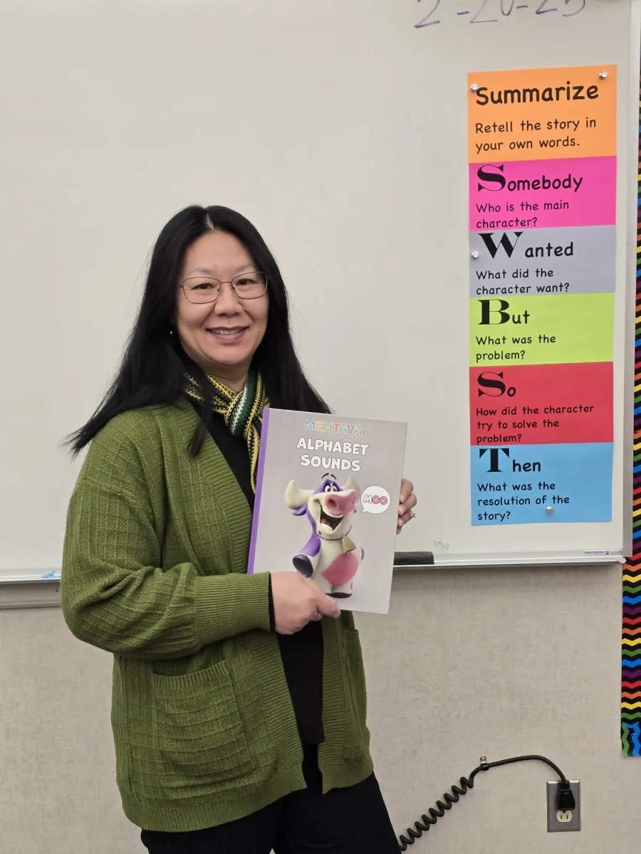 Educator holding the Alphabet Sounds hardcover book in a classroom