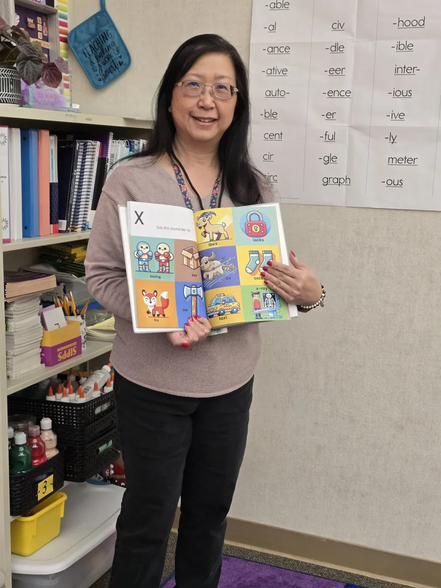 Educator holding open the Alphabet Sounds book to the x sound page